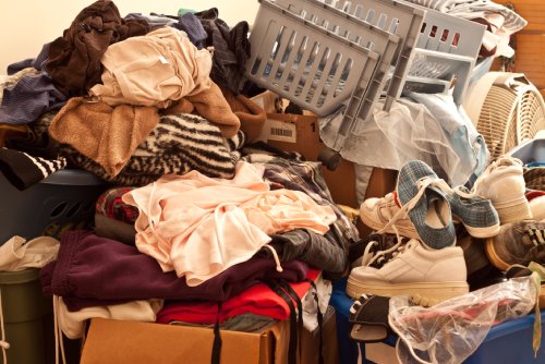 A close up of a pile of items scattered in a room. There are clothes, shoes, and boxes stacked on each other.